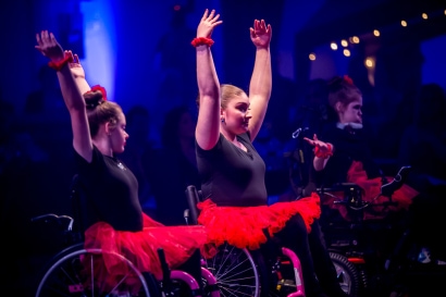 students perform while in wheel chairs and wearing red tutus