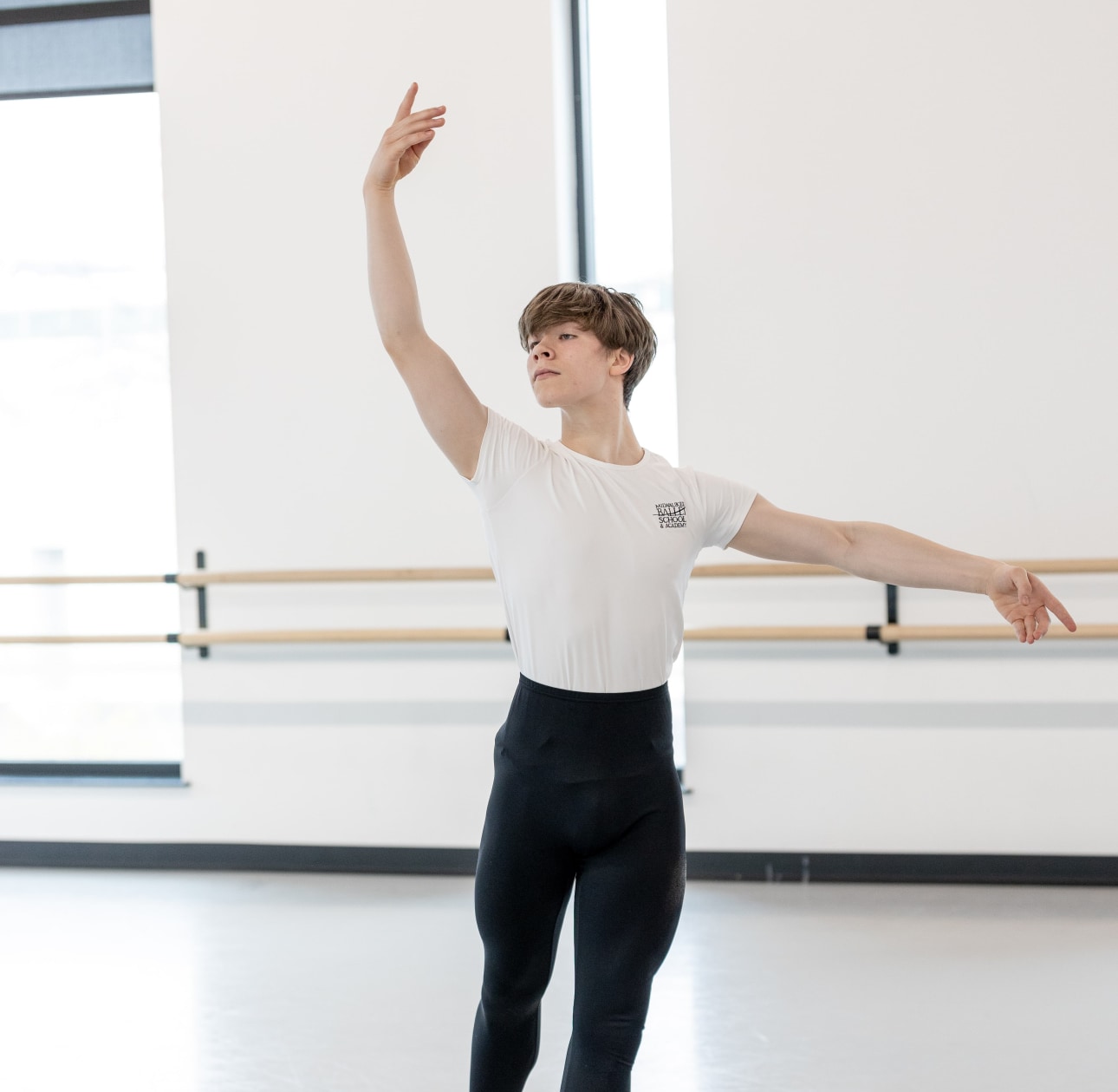 a boy in a white shirt and black pants dancing in a white studio