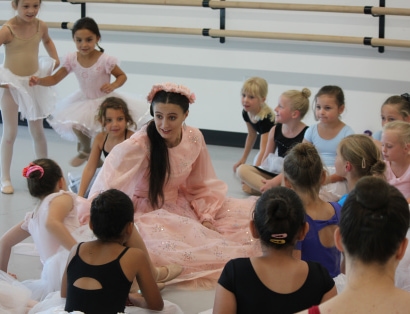 Aurora visits dance camp and the students are circled around her