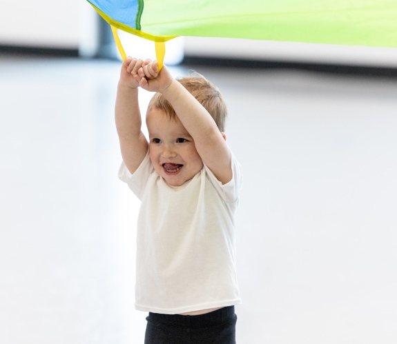 a toddler enjoying some parachute time in class