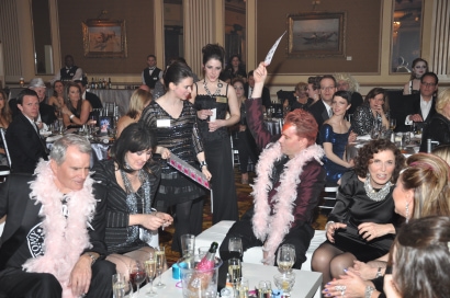 guests enjoy dinner at The Ball, in black attire with pink feather boas