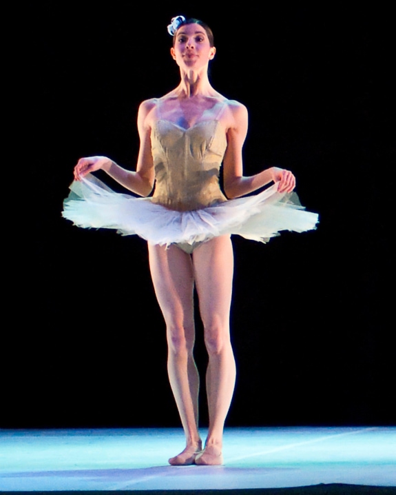a ballerina in a simple, nude tutu, with a feather in her hair