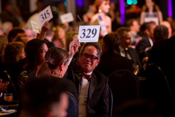 A donor holds up his bidder number during the Ballet Ball live appeal