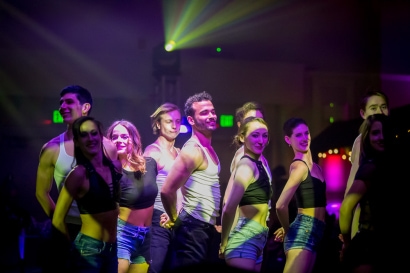 Dancers perform under dim lights with yellow spotlights
