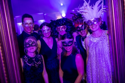 seven people pose in masks and purple lighting in the back