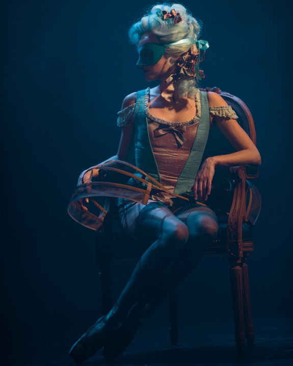 A girl sits tied up to a chair, in a scandalous outfit