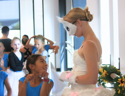 A young dancer admiring the older ballerina, wearing a white cat costume