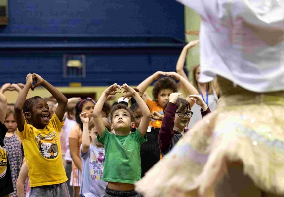 children at a school, taking ballet class from a ballerina in a sparkly tutu