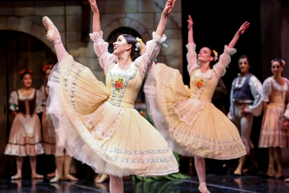 Alana Griffith dancing with her leg in a la seconde, with pointe shoes, and a yellow dress
