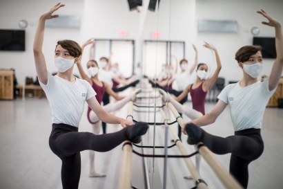 a group of people wearing masks and standing on a barre